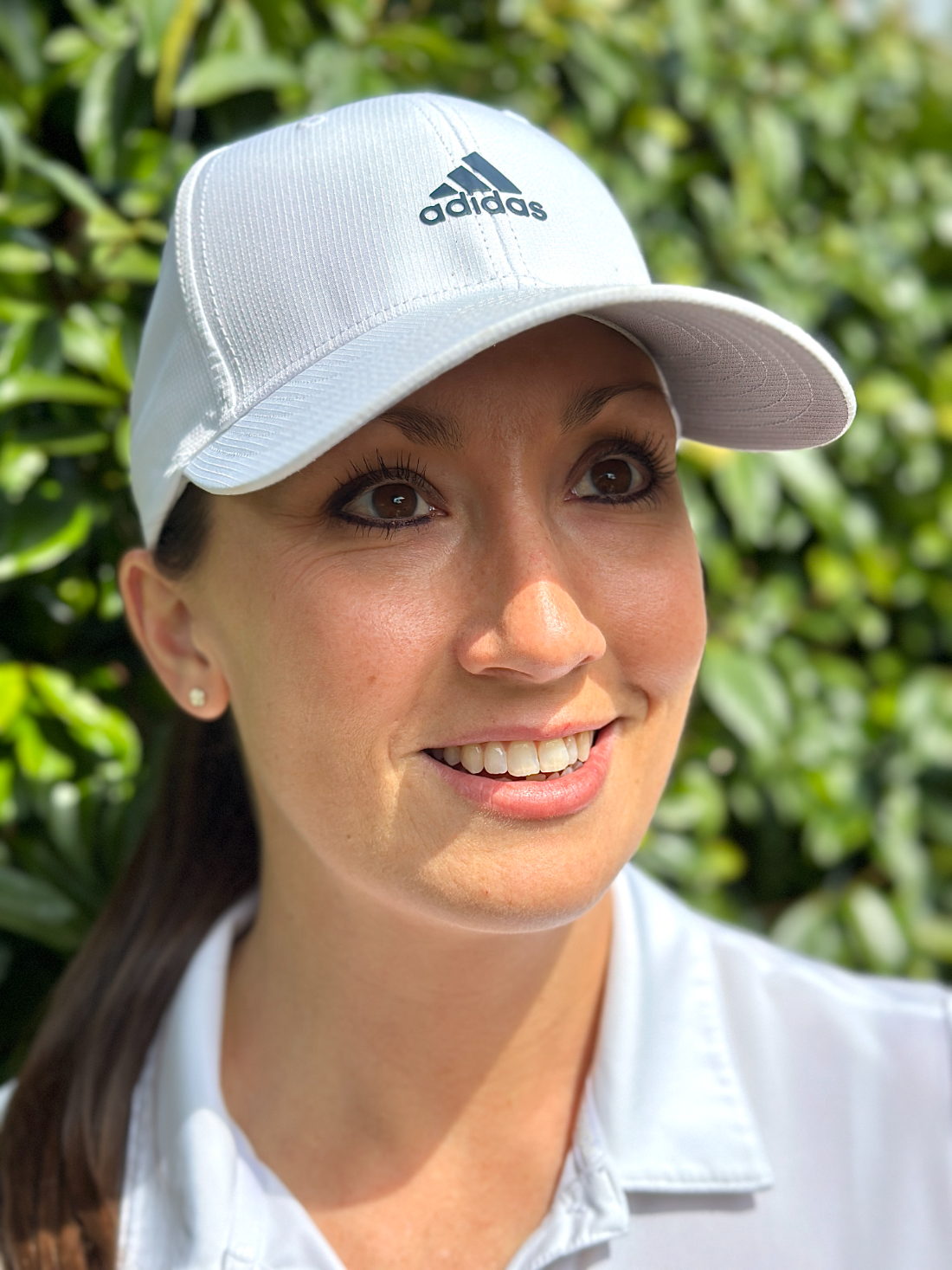 Jess Ratcliffe on the course, wearing a white cap and polo
